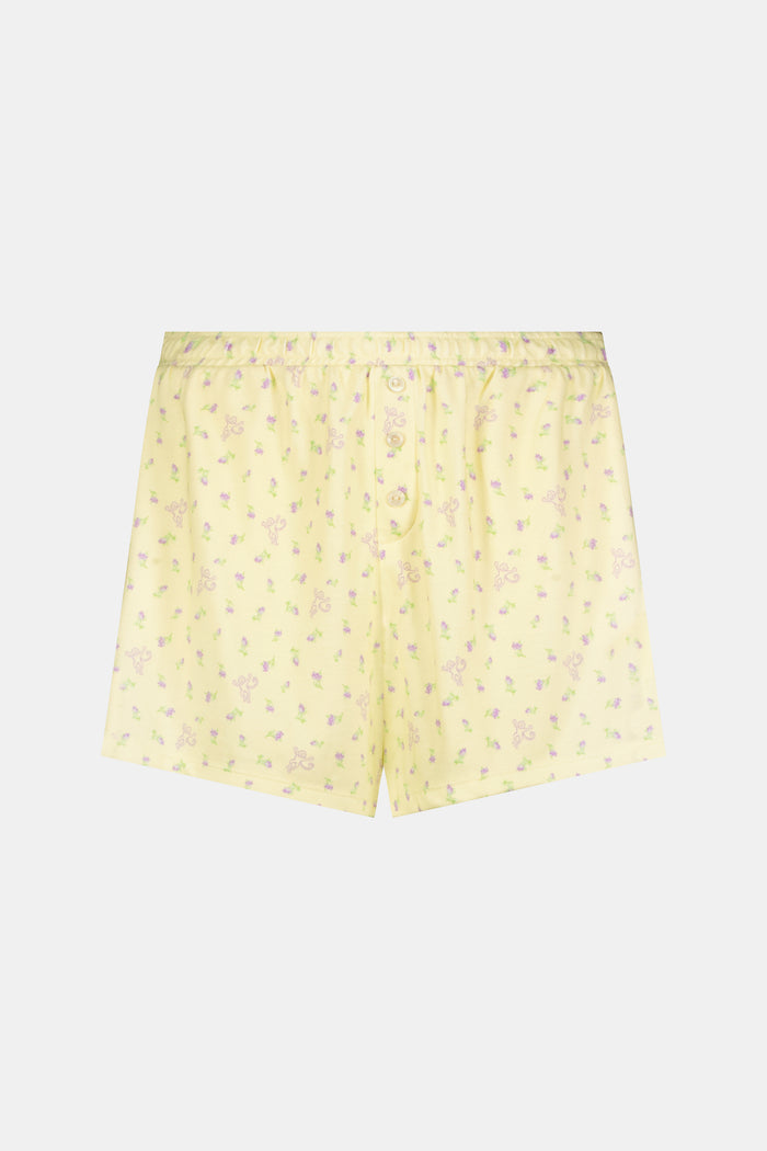The Mini Monkey Blossom Brooklyn Boxer by Roller Rabbit features light yellow Pima cotton with a delicate pastel floral print and an elastic waistband. Displayed on a plain white background, these comfortable women’s loungewear sleep shorts are perfect for relaxing at home.