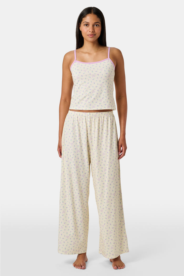 A yellow Mini Monkey Blossom Clarkson Cami by Roller Rabbit, featuring spaghetti straps, a small floral print, and purple trim along the neckline and straps, displayed on a plain white background. This camisole pairs perfectly with the Monroe Lounge Pant for a coordinated look.