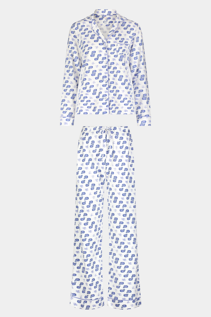 A woman stands barefoot in the Roller Rabbit Moby Long Sleeve Polo Pajamas, featuring a blue geometric-patterned white top and pants. Made from soft pima cotton, the comfy set is shown against a plain white background.