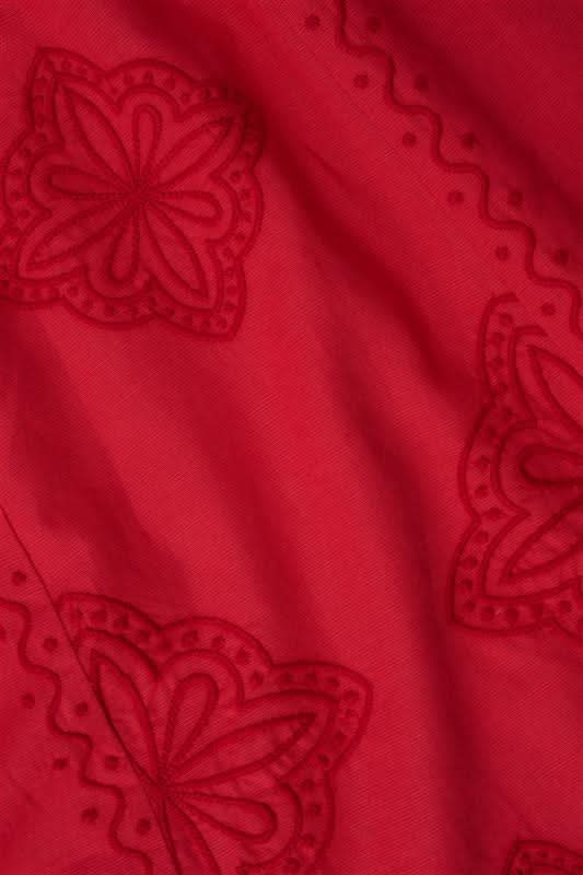 A woman with long curly hair wears the Roller Rabbit Monaco Geo Penelope Dress, a sleeveless, halter-neck, ankle-length red dress with subtle embroidery. She stands forward in open-toed, low-heeled sandals against a plain white background.