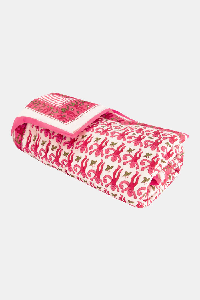 The Monkey Baby Quilt by Roller Rabbit is a soft cotton quilt with a pink and white floral pattern, green accents, intricate pink designs, a contrasting pink border, and a decorative patch in one corner.