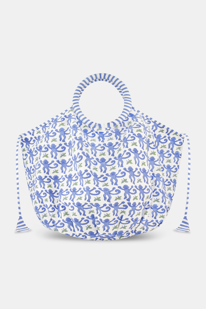 The SAPPHIRE Monkey Bondi Bag is a large cotton canvas tote with blue and white floral patterns, round striped handles, and drawstring ties—ideal for weekend getaways. Shown against a plain light background.
