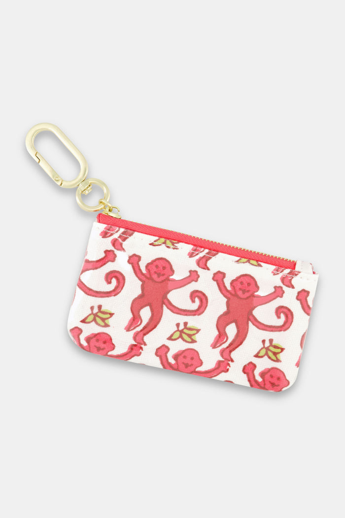 The Roller Rabbit Monkey Coin Pouch features water-resistant cotton canvas, a gold keychain clasp, red zipper, and playful pink monkeys with yellow bananas on a white background.