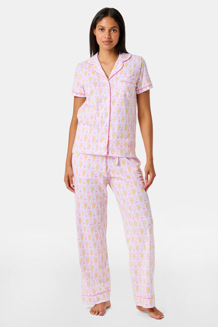 Introducing the Monkey Fiora Pajamas from Roller Rabbit—crafted from fabric adorned with a delightful pattern of pink and yellow monkeys with curled tails and smiling faces, interspersed with tiny leaves on a crisp white background. Perfect for adding playful charm to your sleepwear collection.
