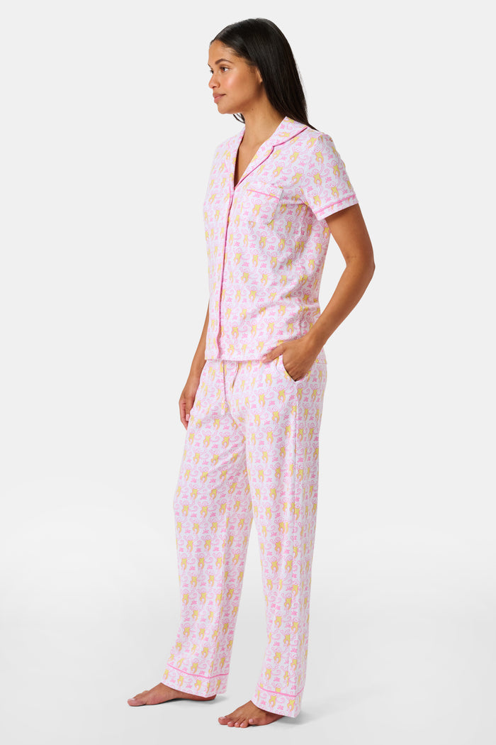 Introducing the Monkey Fiora Pajamas from Roller Rabbit—crafted from fabric adorned with a delightful pattern of pink and yellow monkeys with curled tails and smiling faces, interspersed with tiny leaves on a crisp white background. Perfect for adding playful charm to your sleepwear collection.