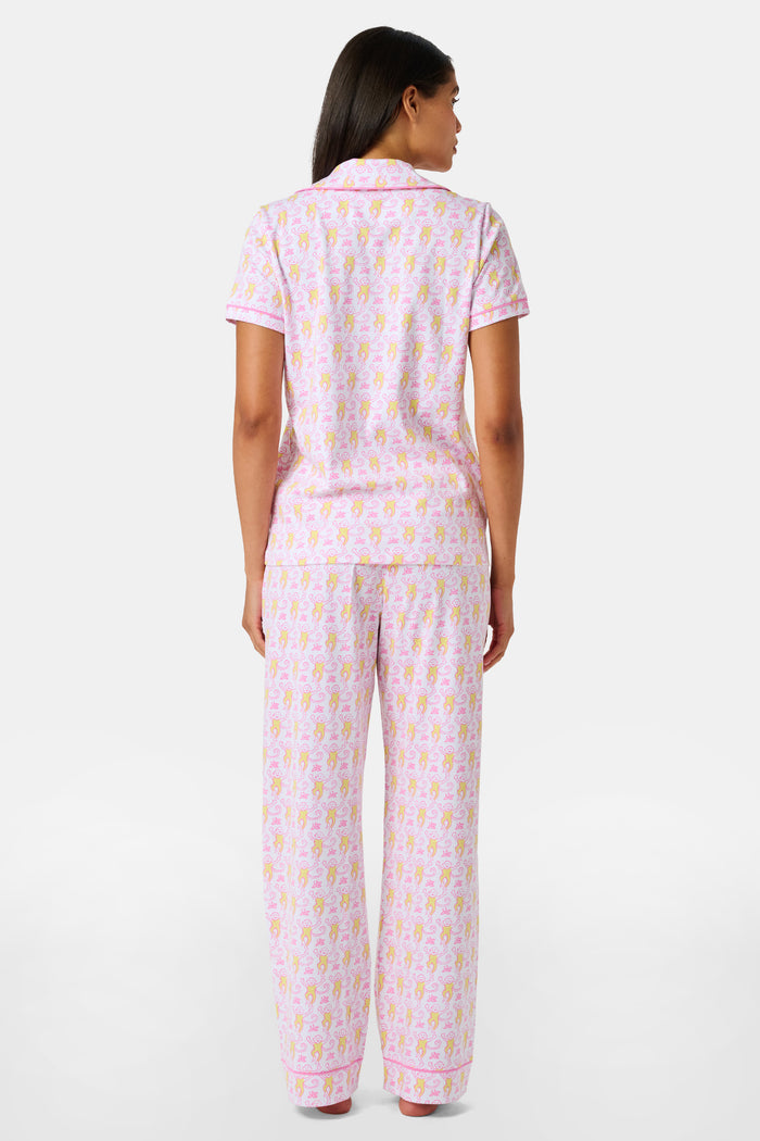 Introducing the Monkey Fiora Pajamas from Roller Rabbit—crafted from fabric adorned with a delightful pattern of pink and yellow monkeys with curled tails and smiling faces, interspersed with tiny leaves on a crisp white background. Perfect for adding playful charm to your sleepwear collection.