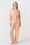 A smiling woman stands barefoot against a light background, wearing Roller Rabbit's Monkey Long Sleeve Polo Pajamas—a matching women's comfy PJs set with long sleeves and pants.