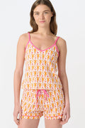 A woman wears the Roller Rabbit Monkey Mischa Set, a white Pima cotton pajama with an orange and pink monkey print, featuring a sleeveless top with pink straps and matching shorts with a pink drawstring, standing against a plain white background.