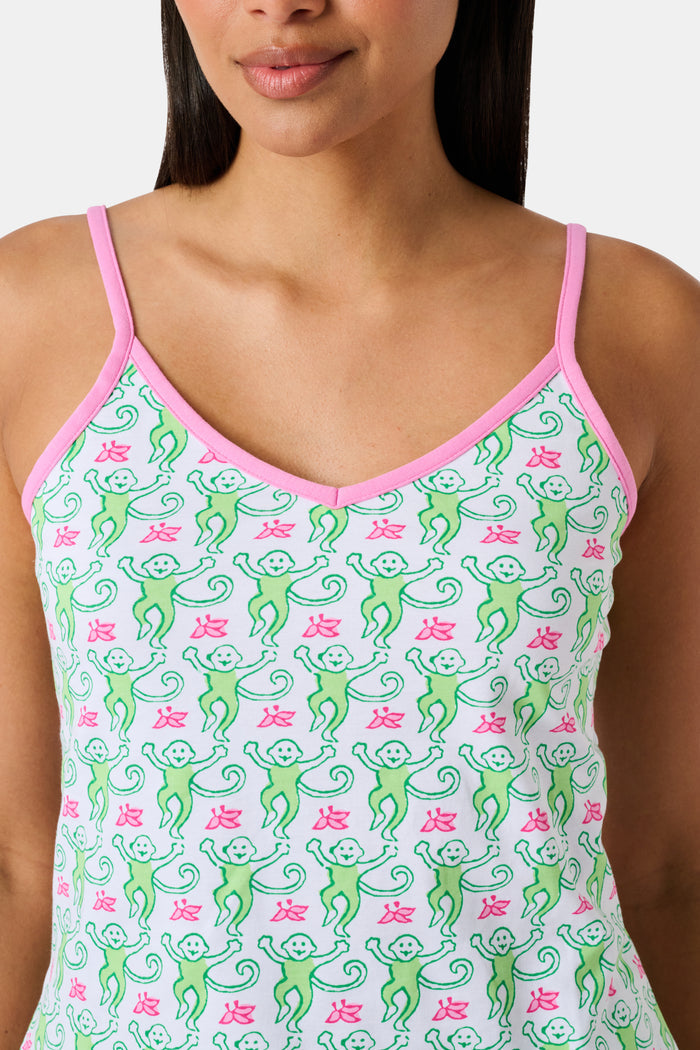 A woman wearing the SERFLEX Monkey Mischa Set, a coordinated sleeveless top and shorts with pink straps and a fun pink and green flamingo print, made from soft Pima cotton, stands against a plain white background.