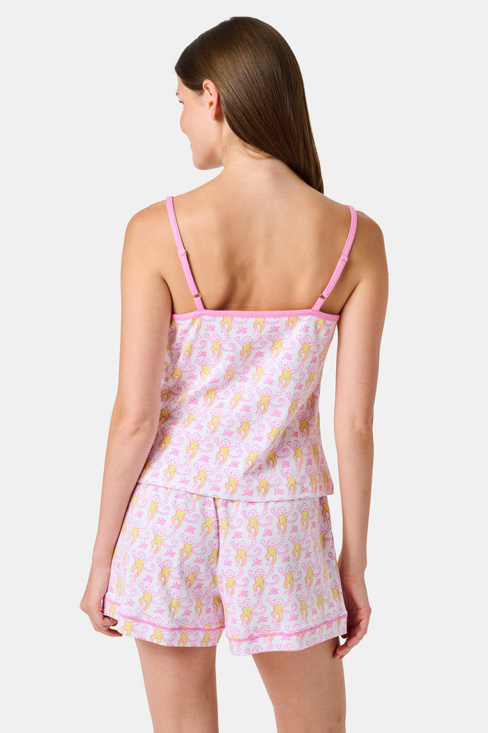 A woman wearing the Roller Rabbit Monkey Mischa Set stands with one hand in her pocket against a plain white background. This pajama set features a light pink flamingo print camisole and matching shorts, crafted from soft Pima cotton for comfort and style in women’s sleepwear.