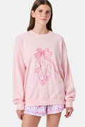 A person with long blonde hair in a ballet slipper-pink Roller Rabbit Monkey Pirouette Andie Sweatshirt holds patterned folders in front of white lockers.