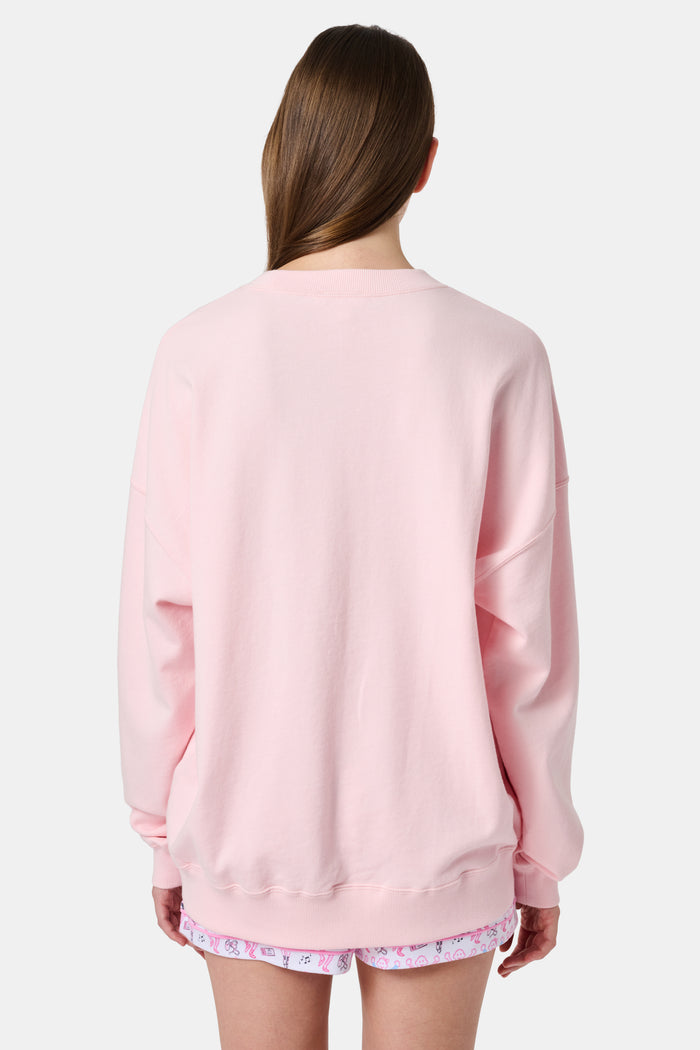 A person with long blonde hair in a ballet slipper-pink Roller Rabbit Monkey Pirouette Andie Sweatshirt holds patterned folders in front of white lockers.