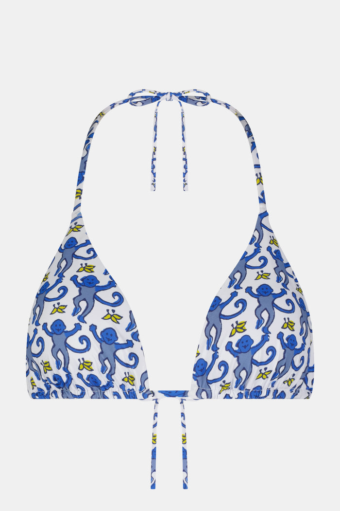 A woman wearing the Roller Rabbit Monkey/Hearts Serena Bikini Top, a white halter-style swim top with blue hearts, stands against a plain background and smiles softly.
