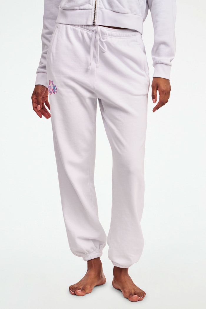 A person stands barefoot in Roller Rabbit O.C. Monkey Sweatpants and a matching hoodie, featuring colorful embroidered and printed graphics near the left pocket. The background is plain white.