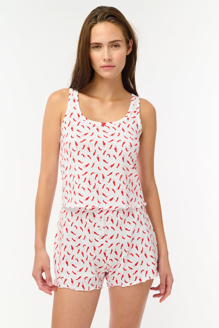 A woman wears the Picante Astor Tank by Roller Rabbit, featuring a scoop neck and red pepper print. Her brown hair is loose and her face partly out of frame. The look is casual and summery.