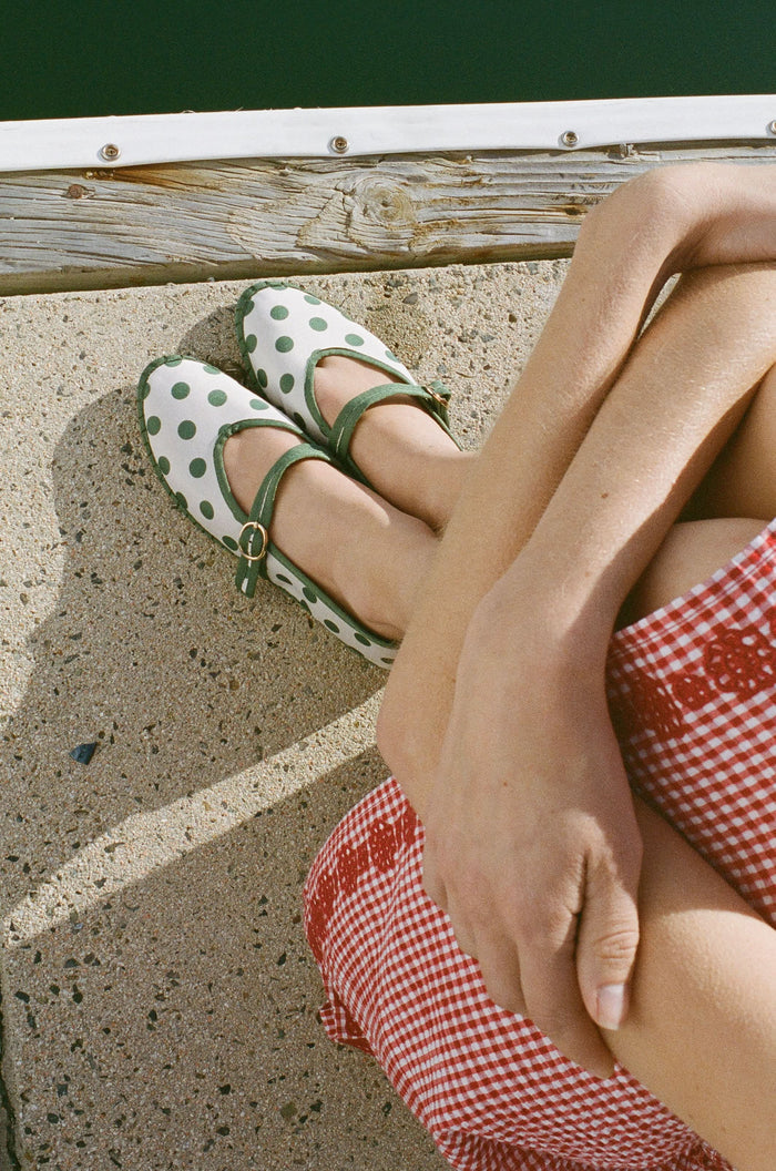 The FLABELUS Polka Dot Pierre is a cream Mary Jane flat with green polka dots, a green sole, and a green strap with a gold buckle, shown side view on a plain white background.