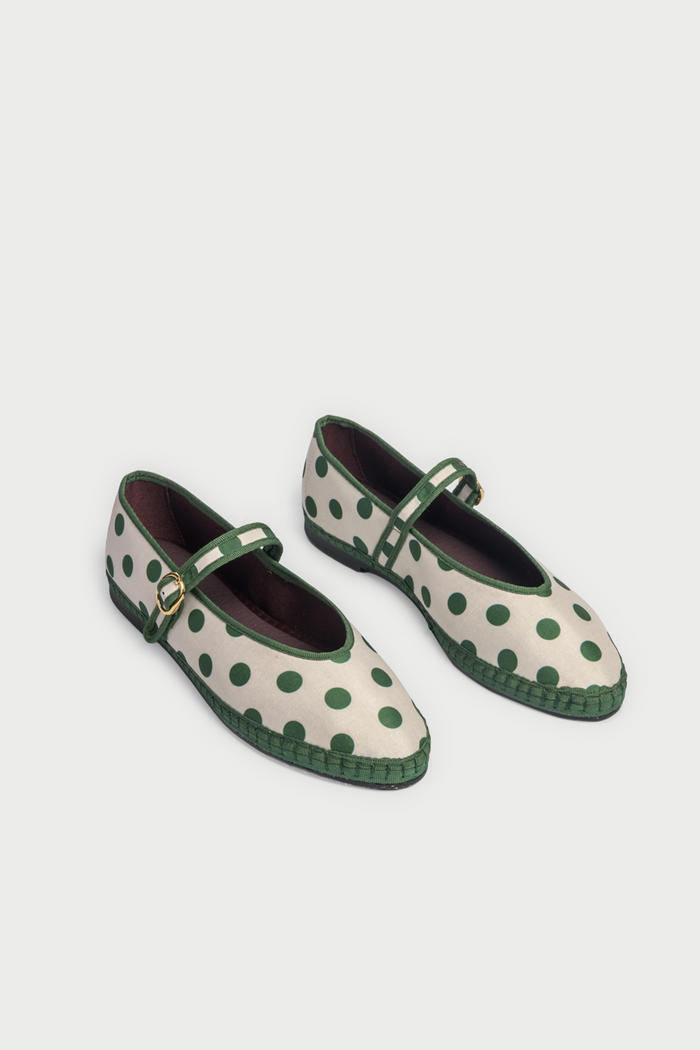 The FLABELUS Polka Dot Pierre is a cream Mary Jane flat with green polka dots, a green sole, and a green strap with a gold buckle, shown side view on a plain white background.