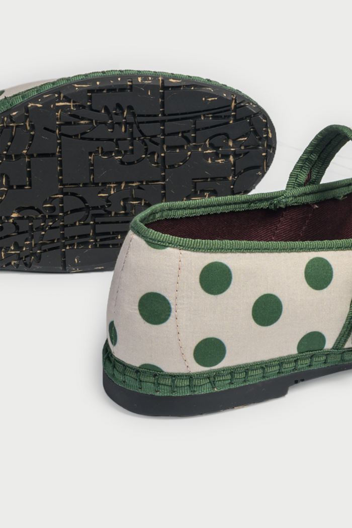 The FLABELUS Polka Dot Pierre is a cream Mary Jane flat with green polka dots, a green sole, and a green strap with a gold buckle, shown side view on a plain white background.