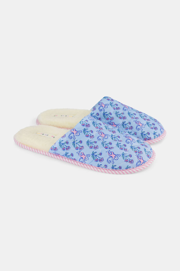 The Rosa Ditsy Monkey Quilted Slippers by Roller Rabbit feature a blue floral pattern, pink striped soles, and faux-shearling lining, displayed side by side on a white background.