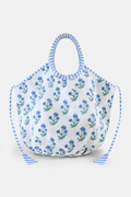 The Rosa Floral Bondi Bag by Roller Rabbit is a white cotton canvas tote with blue floral patterns, round padded handles wrapped in blue and white stripes, and matching striped ties—perfect for daily use.