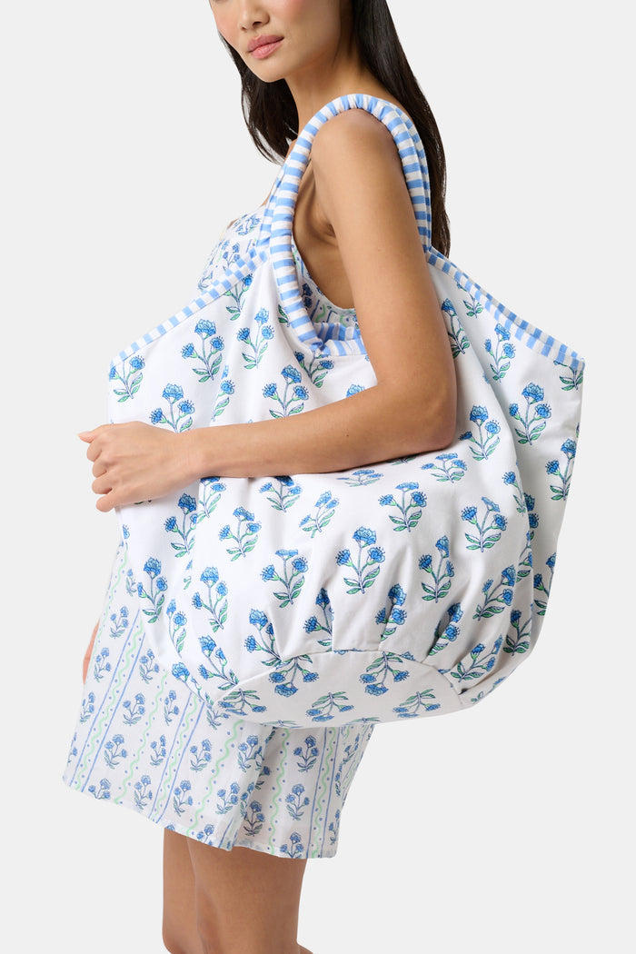 The Rosa Floral Bondi Bag by Roller Rabbit is a white cotton canvas tote with blue floral patterns, round padded handles wrapped in blue and white stripes, and matching striped ties—perfect for daily use.