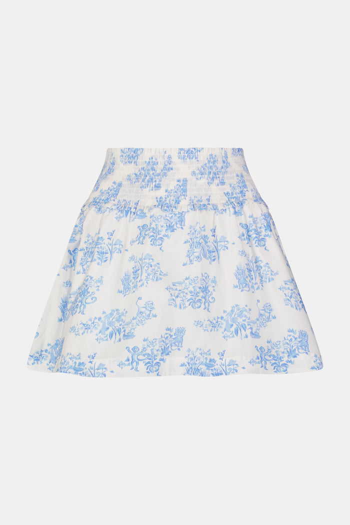A person wears a matching blue and white Sherwood Forest Monkey Delphine Mini Nap Skirt by Roller Rabbit and a ruffled crop top, standing against a plain background.
