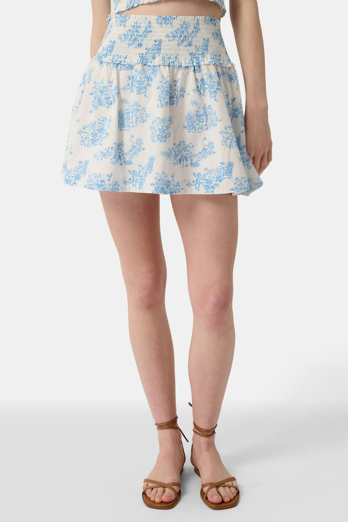 A person wears a matching blue and white Sherwood Forest Monkey Delphine Mini Nap Skirt by Roller Rabbit and a ruffled crop top, standing against a plain background.
