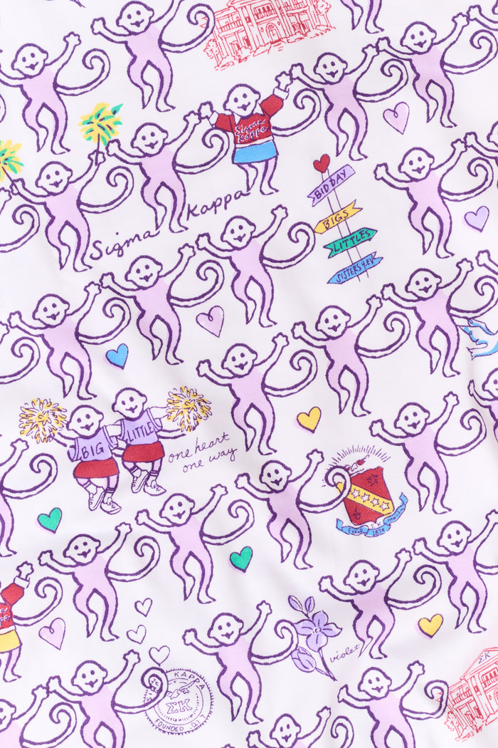 The Sigma Kappa Monkey Pajamas by Roller Rabbit is a long-sleeve set featuring a buttoned top and comfortable elastic waist, decorated with an all-over pattern of colorful cartoon monkey faces on a white background.