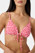 A woman wears the Roller Rabbit Starry Dot Isa Bikini Top, a red triangle bikini with white polka dots and a front tie, shown from shoulders to waist against a plain background.