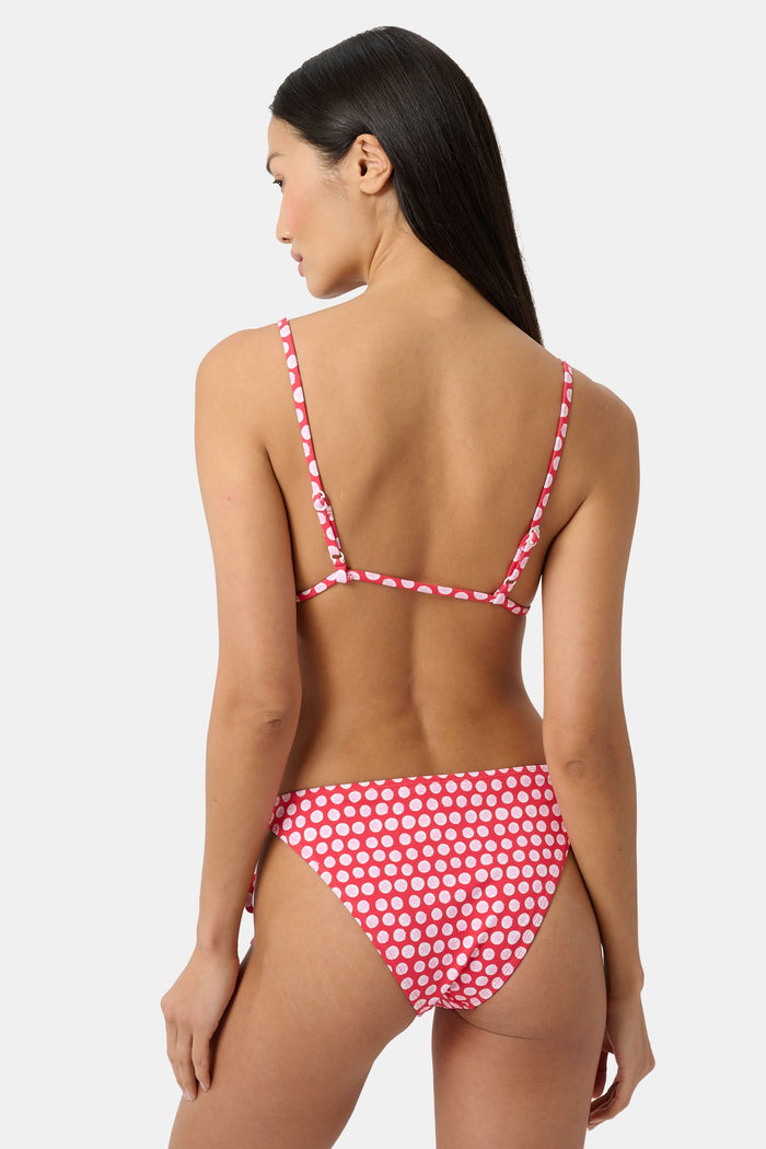 A woman wears the Roller Rabbit Starry Dot Isa Bikini Top, a red triangle bikini with white polka dots and a front tie, shown from shoulders to waist against a plain background.