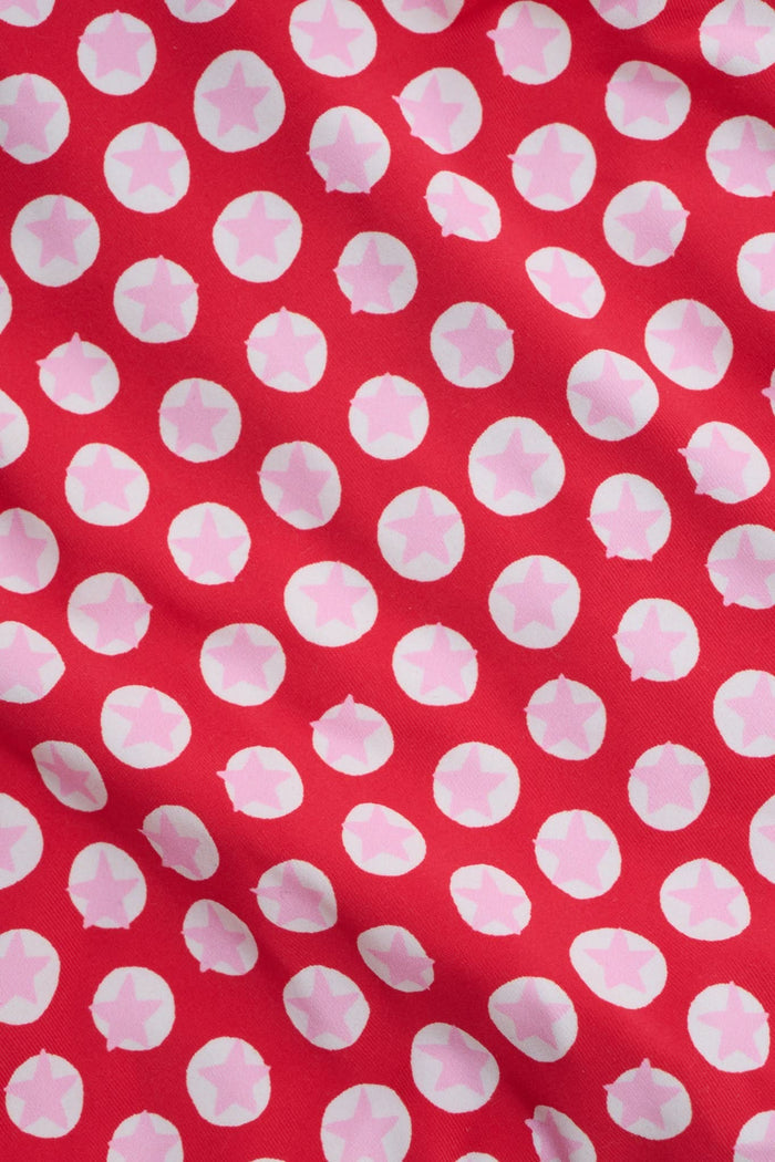 A person wears the Roller Rabbit Starry Dot Isa Bikini Bottom in red with white polka dots and adjustable hip ties, shown from mid-torso to upper thigh.