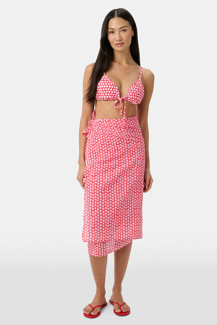 A woman models the Roller Rabbit Starry Dot Pareo with a pink and white bikini top and red flip-flops, standing against a light background.