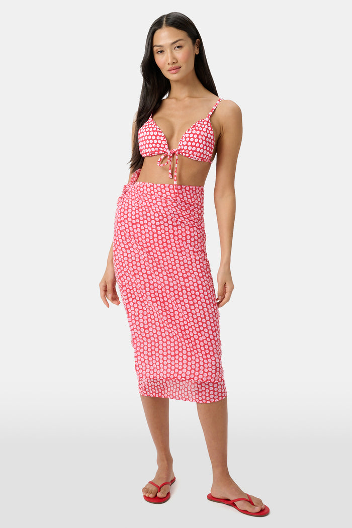 A woman models the Roller Rabbit Starry Dot Pareo with a pink and white bikini top and red flip-flops, standing against a light background.