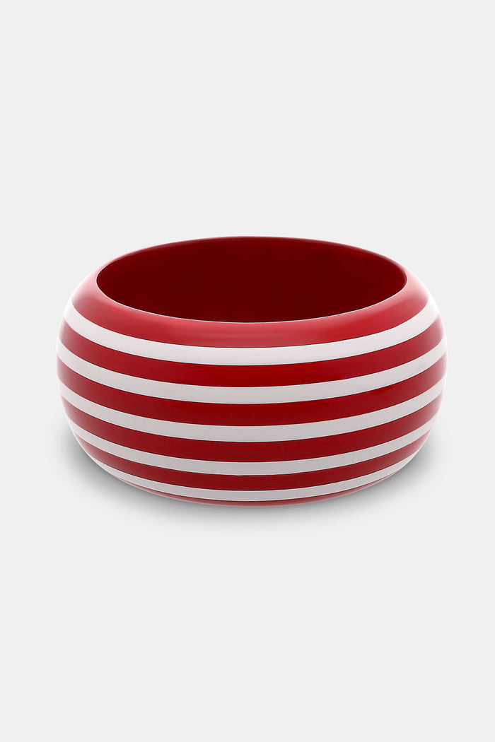 The Roller Rabbit Striped Bangle is a wide, round wooden bracelet with a glossy red finish and evenly spaced hand-painted white stripes, shown on a plain light gray background.
