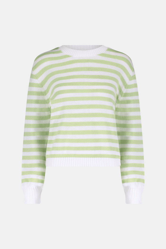 A woman with straight brown hair wears the Roller Rabbit Striped Hadley Sweater in sage green and white stripes, paired with white high-waisted pants and a beaded necklace, standing against a plain background and looking at the camera.