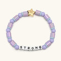 Lavender beaded bracelet with a gold star tag and letter beads spelling 'STRONG' on a white background