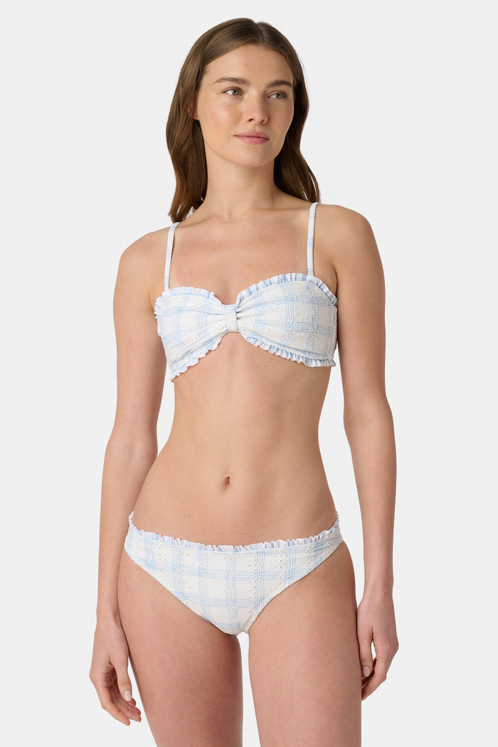 A woman wears the Roller Rabbit Sun Check Eyelet Sydney Bikini Top, featuring ruffle trim and adjustable straps, against a plain light background.