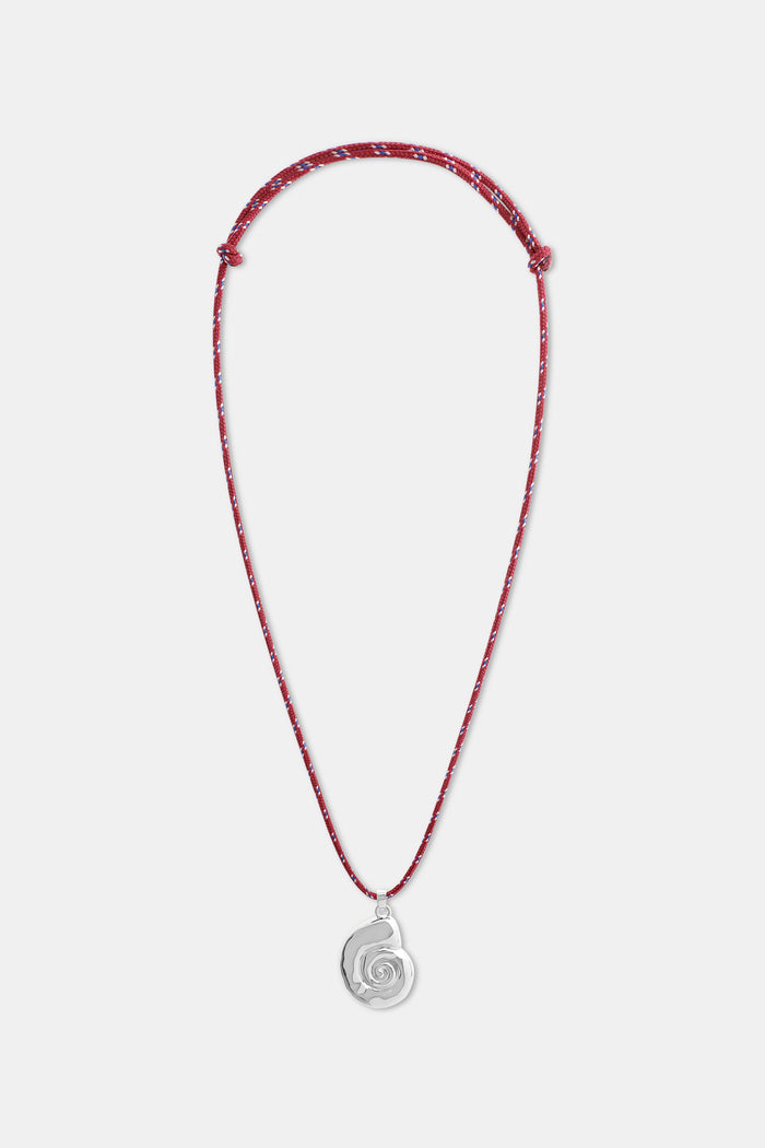 A woman wears a white shirt and the Roller Rabbit Swirl Cord Necklace—a red cord with a silver shell pendant. Only her lower face, neck, and upper chest are visible.