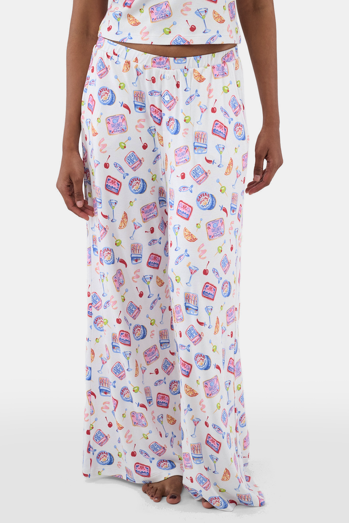 A person wears the Roller Rabbit Tinned or Twist Boden Pant, ultra-soft and white with playful prints. Their matching top complements the wide-leg pull-on pants, and they are barefoot.