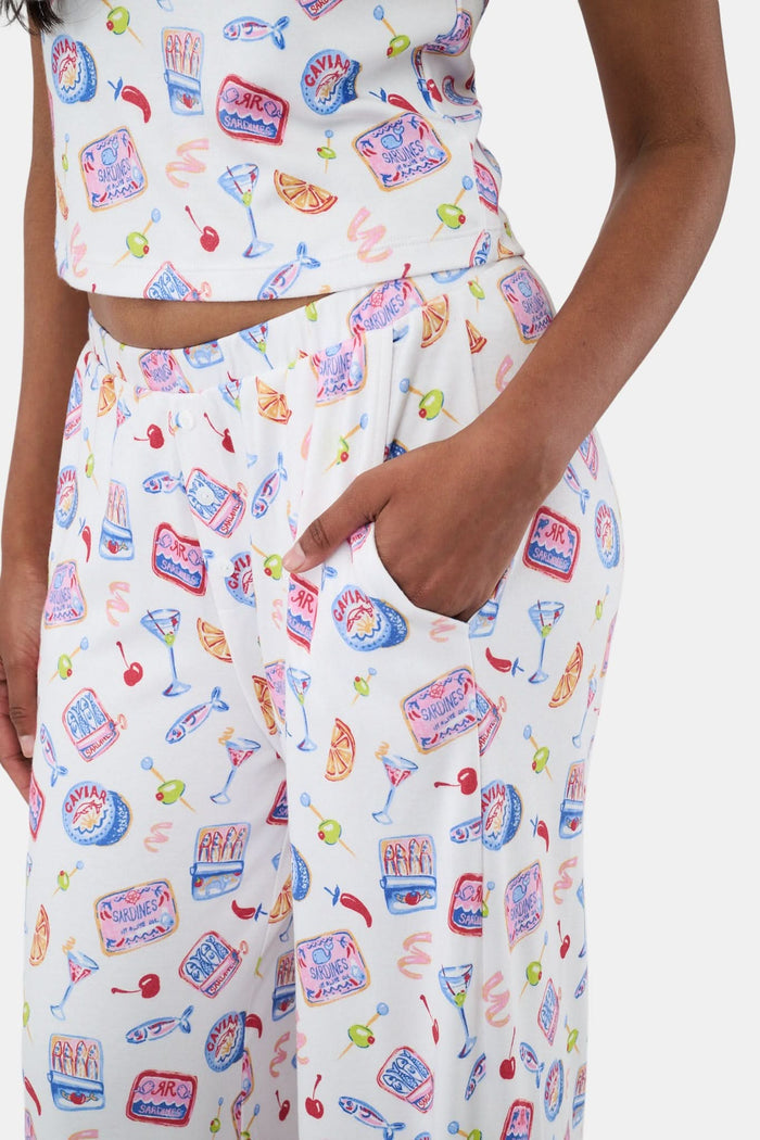 A person wears the Roller Rabbit Tinned or Twist Boden Pant, ultra-soft and white with playful prints. Their matching top complements the wide-leg pull-on pants, and they are barefoot.