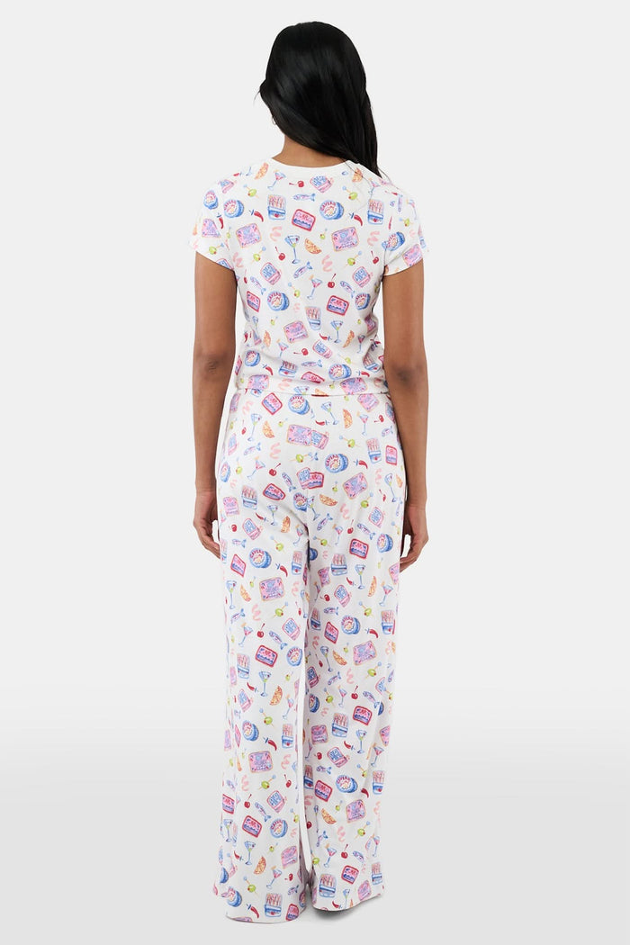 A person wears the Roller Rabbit Tinned or Twist Boden Pant, ultra-soft and white with playful prints. Their matching top complements the wide-leg pull-on pants, and they are barefoot.