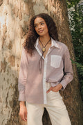 A woman wearing the Roller Rabbit Yarn Dye Stripe Emory Dress—a cotton button-down style with a tie belt and white collar—smiles while looking to the side and pairs the dress with knee-high boots. The background is plain light gray.