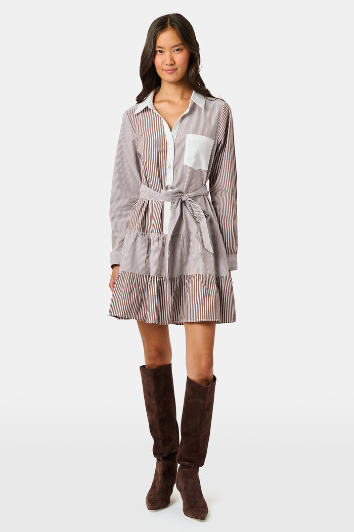 A woman wearing the Roller Rabbit Yarn Dye Stripe Emory Dress—a cotton button-down style with a tie belt and white collar—smiles while looking to the side and pairs the dress with knee-high boots. The background is plain light gray.
